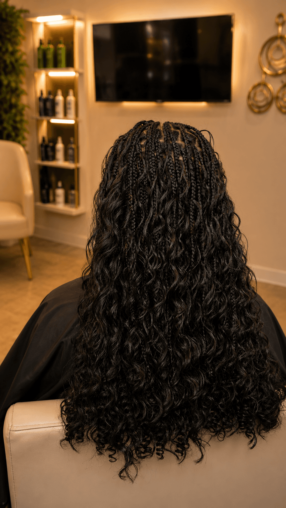 Long black knotless braids with full wavy curly ends — back view