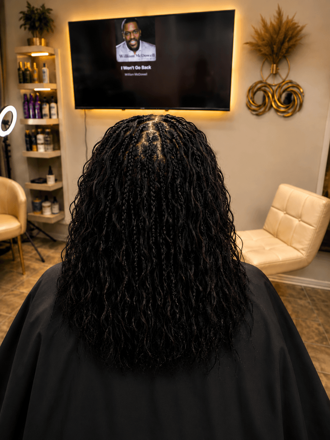 Medium length black knotless braids with curly wavy ends — back view